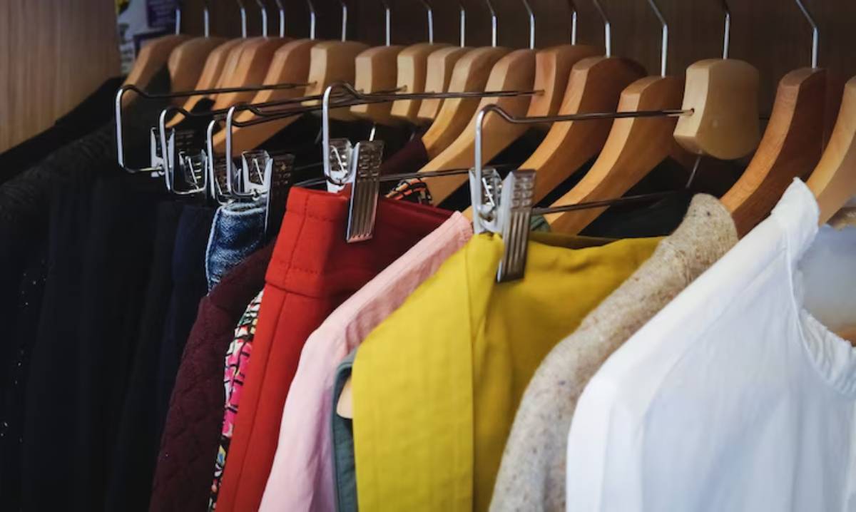 A colorful assortment of clothing hangs neatly on wooden hangers in a boutique display, showcasing various fabrics and styles.