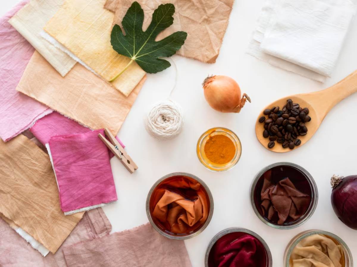 An array of fabric swatches, natural dyes, and organic materials like onion and coffee, for dyeing fabrics, arranged artistically.