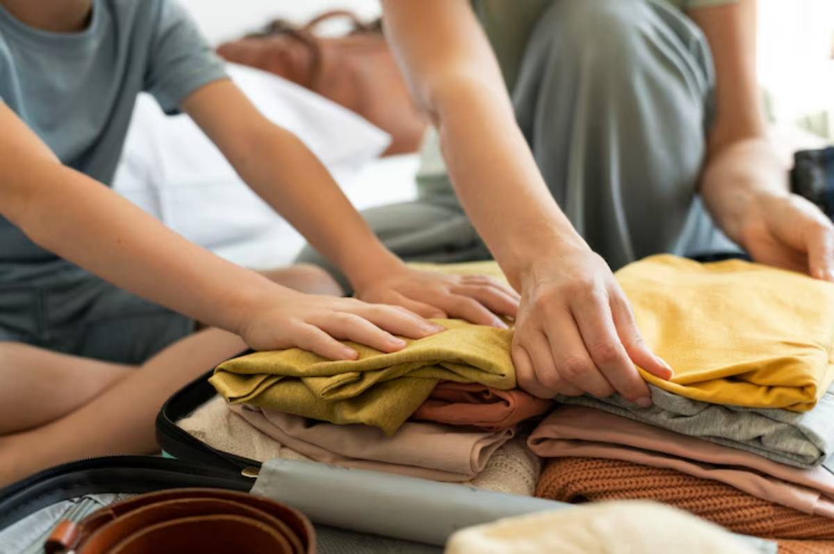 A child and parent folding colorful clothes together while packing a suitcase on a bed, showcasing teamwork and organization.