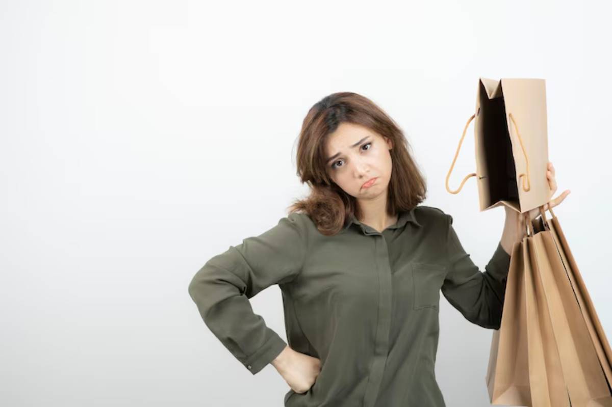 A person in an olive green shirt poses confidently, holding several brown shopping bags and an empty paper bag.