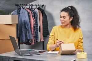 women writing something on a package seeing from a laptop